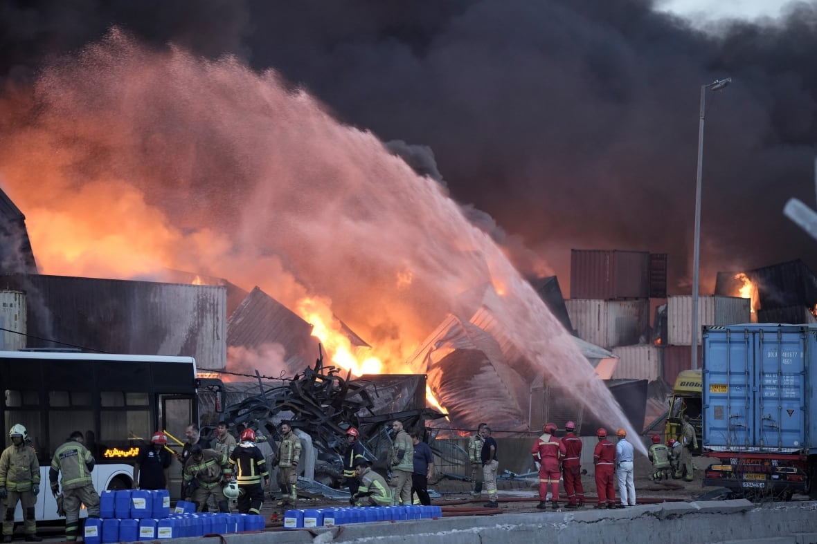 Iran president visits injured, calls for probe into port explosion that killed dozens Firefighters try to extinguish a fire burning amid shipping containers.